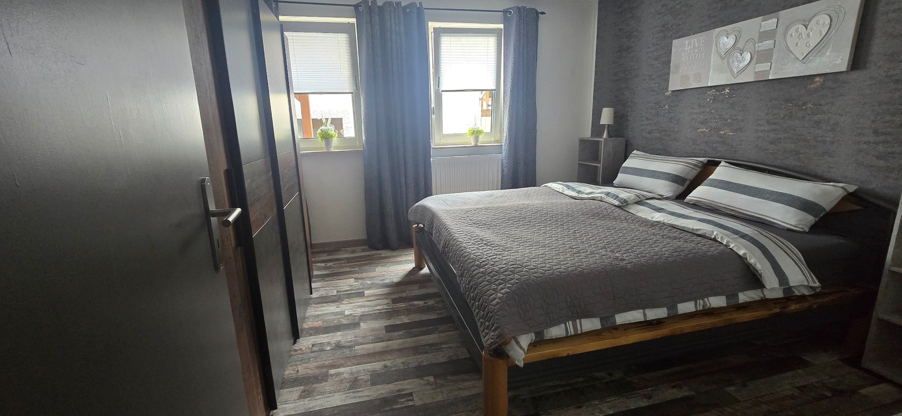 Schlafzimmer mit Doppelbett und zwei Fenstern
